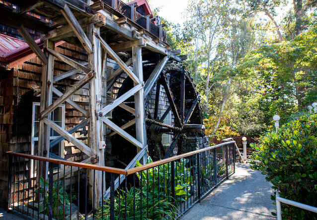 A wooden exterior with a water wheel and pathway