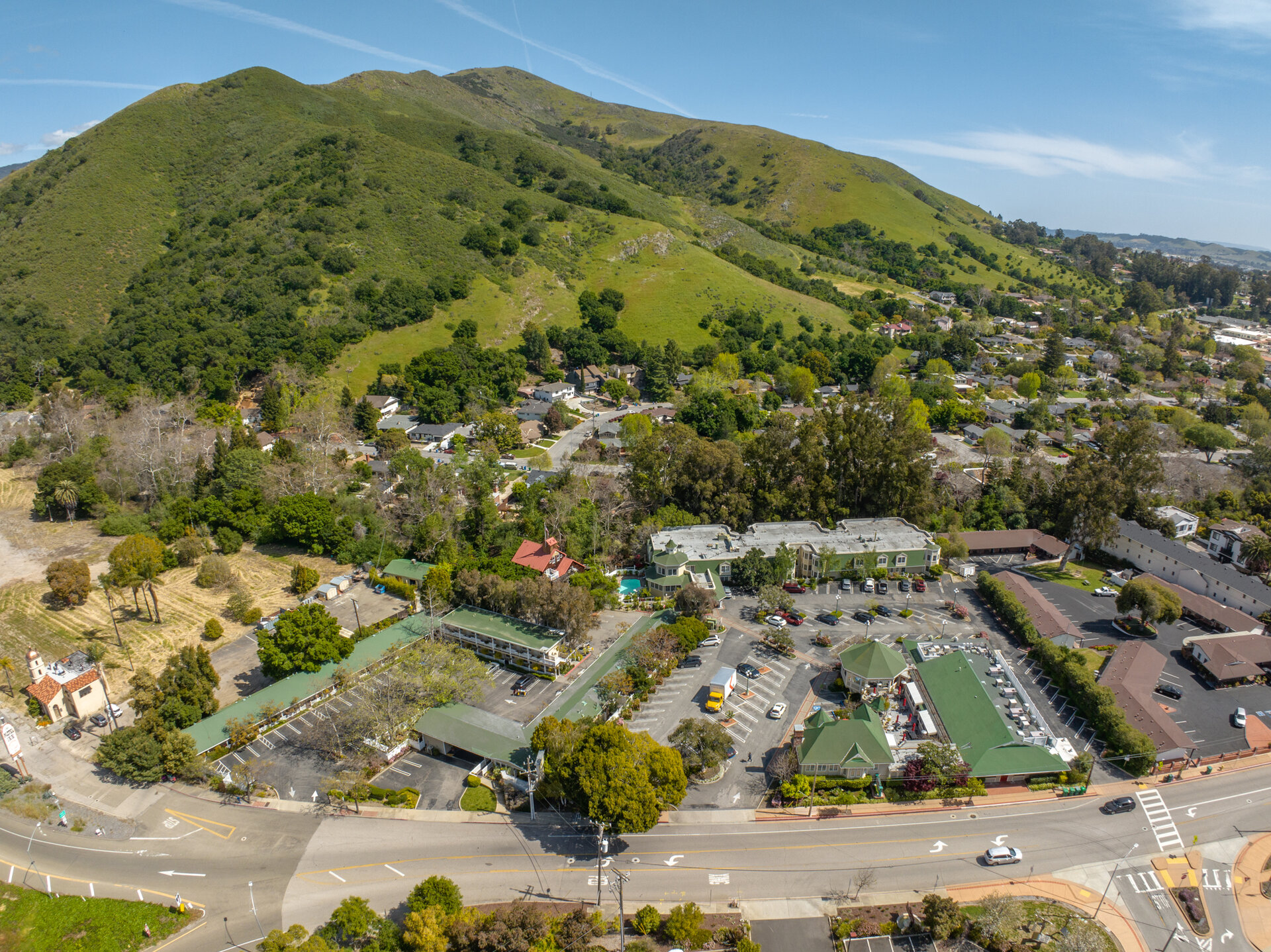 Aerial view of a hotel and its surroundings with a mountain in the background.